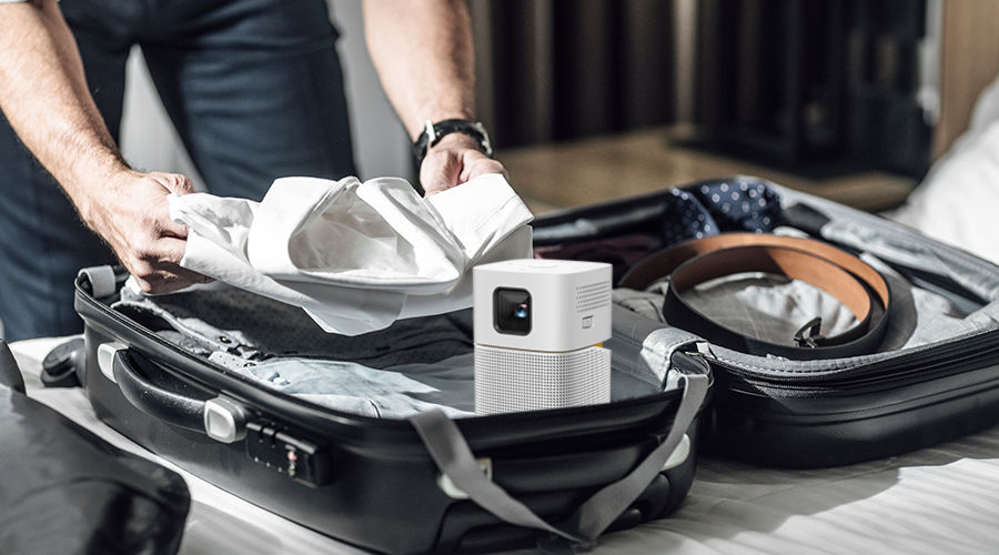 A business man packing up with a portable projector for travel